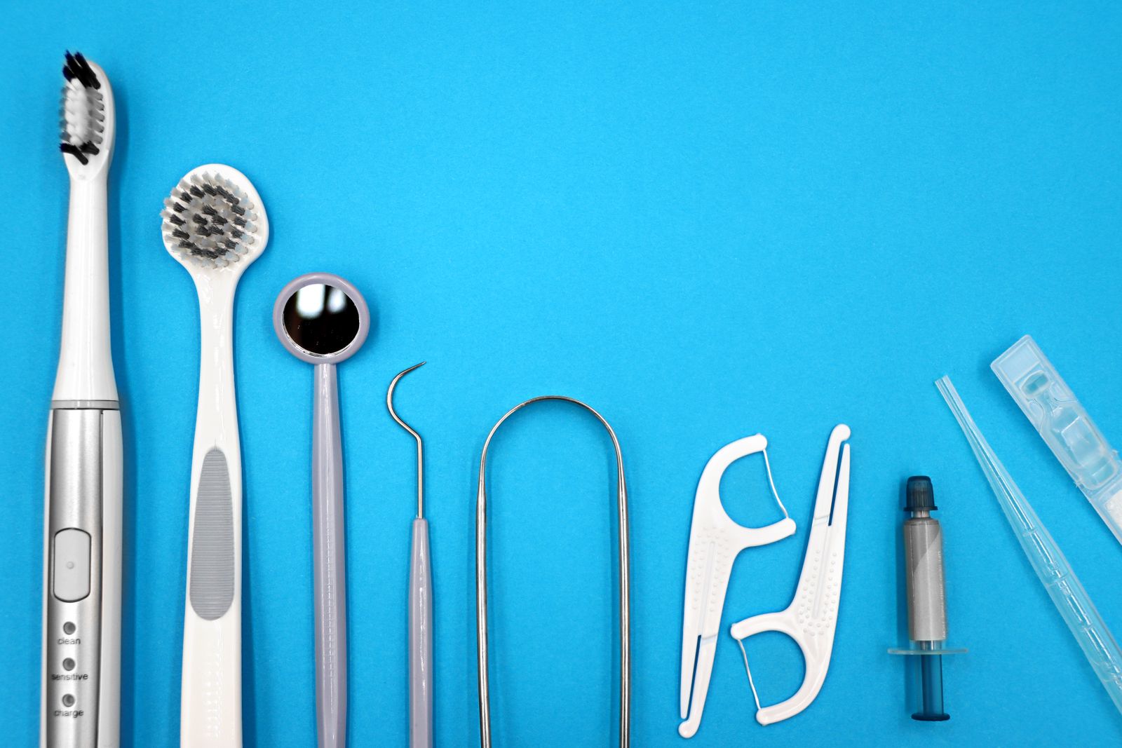 Escovas de dentes, fio dental com suporte e acessórios de higiene sobre fundo azul